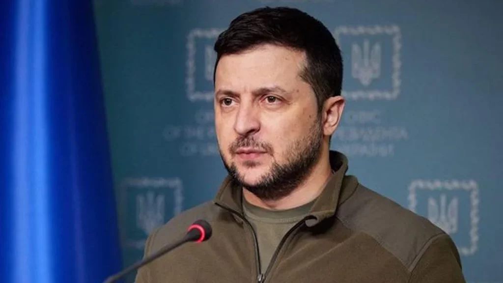 This image has an empty alt attribute; its file name is ukrainian-president-volodymyr-zelensky-speaking-at-a-podium-with-a-ukrainian-flag-in-the-background-1024x576.webp